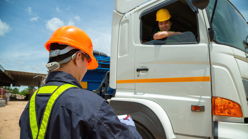 A worker going through a checklist with the driver of a big truck.